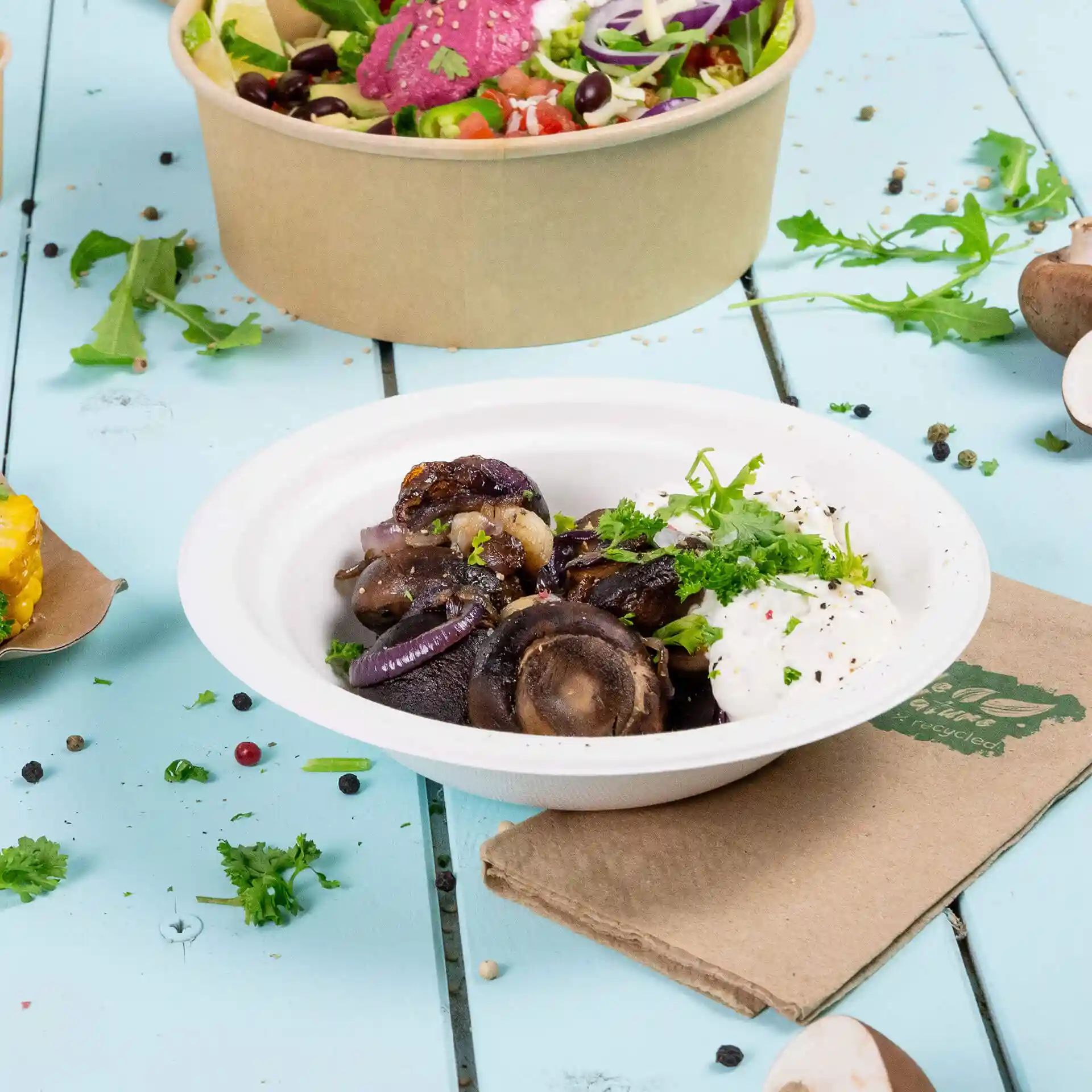 Bol rond profond en sucre blanc contenant des aliments cuits, garni d'herbes, sur une surface en bois bleu.