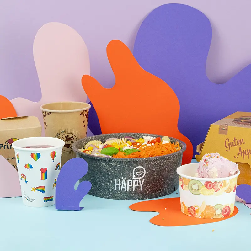 Collection d'articles d'emballage alimentaire imprimés sur mesure, y compris des contenants, des gobelets et un sac avec divers étiquettes de design.