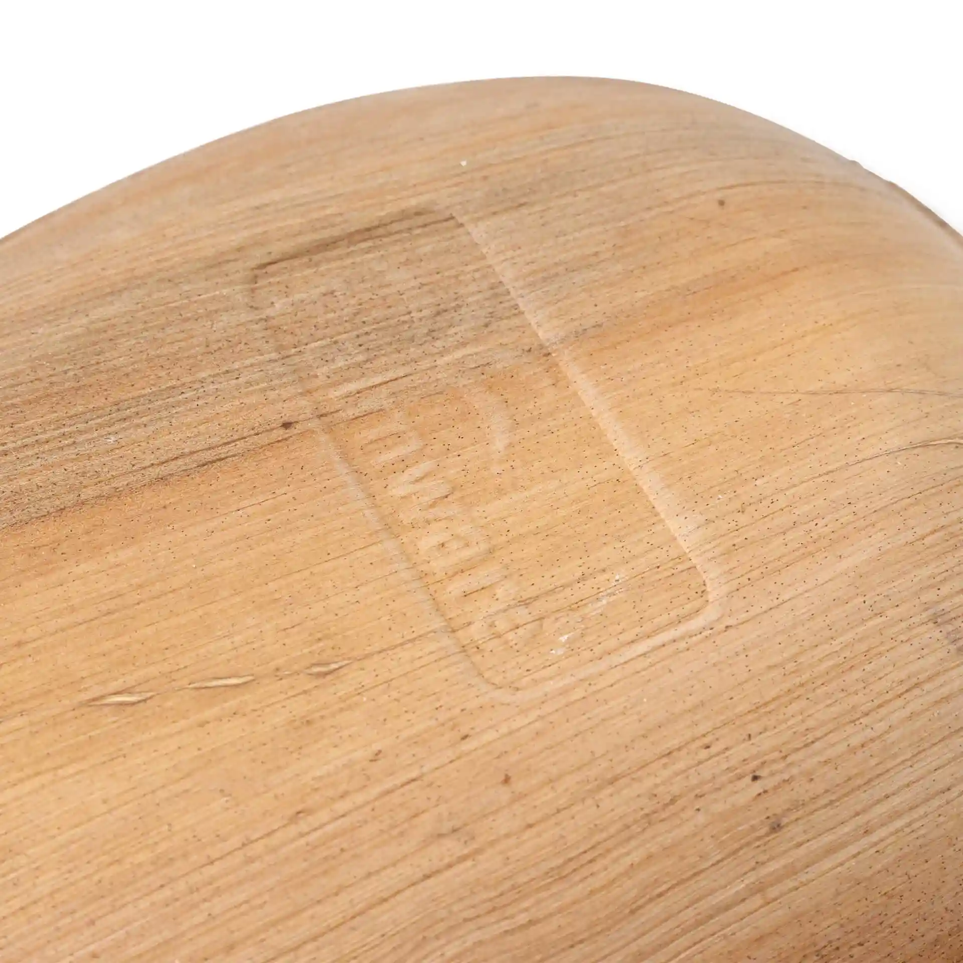 Gros plan d'une assiette en feuille de palmier montrant une texture de grain de bois clair et un logo en relief sur la surface.