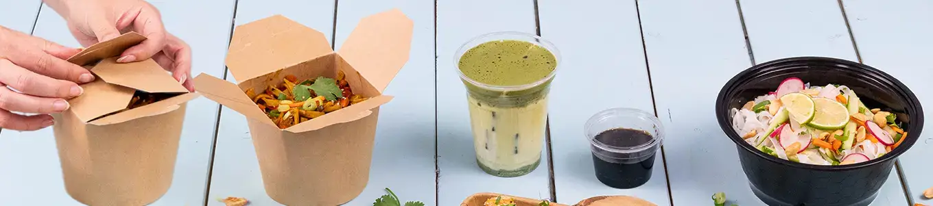 Deux boîtes asiatiques à emporter contenant des nouilles, garnies d'herbes et de piments, placées sur un tapis en bambou.
