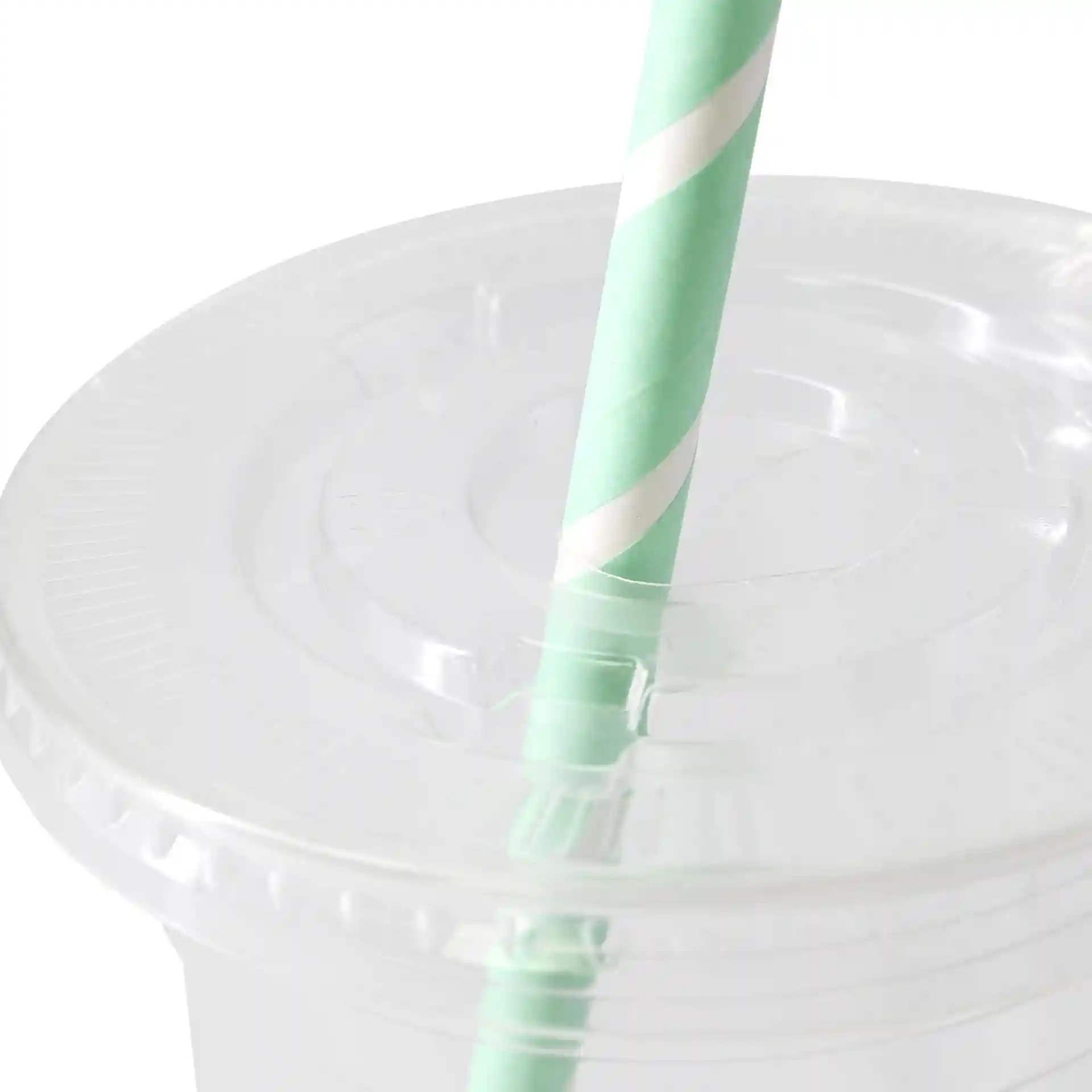 Couvercle plat transparent avec une fente pour paille croisée, diamètre de 95 mm, avec une paille rayée vert menthe et blanche.