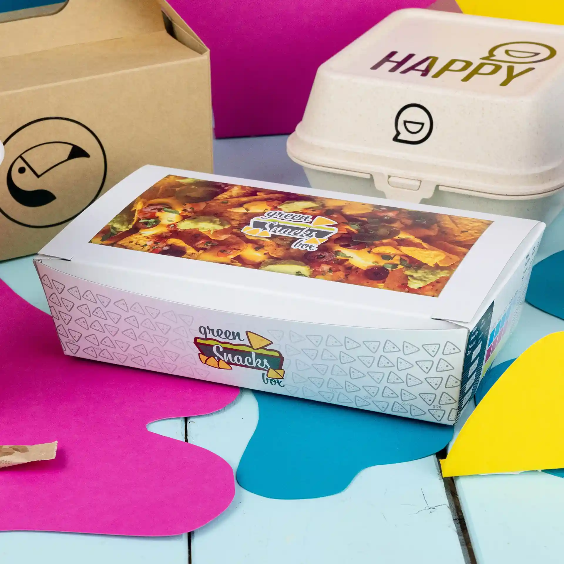 Boîte à snacks avec un design imprimé, capacité de 750 ml, placée sur un fond coloré avec d'autres contenants à proximité.