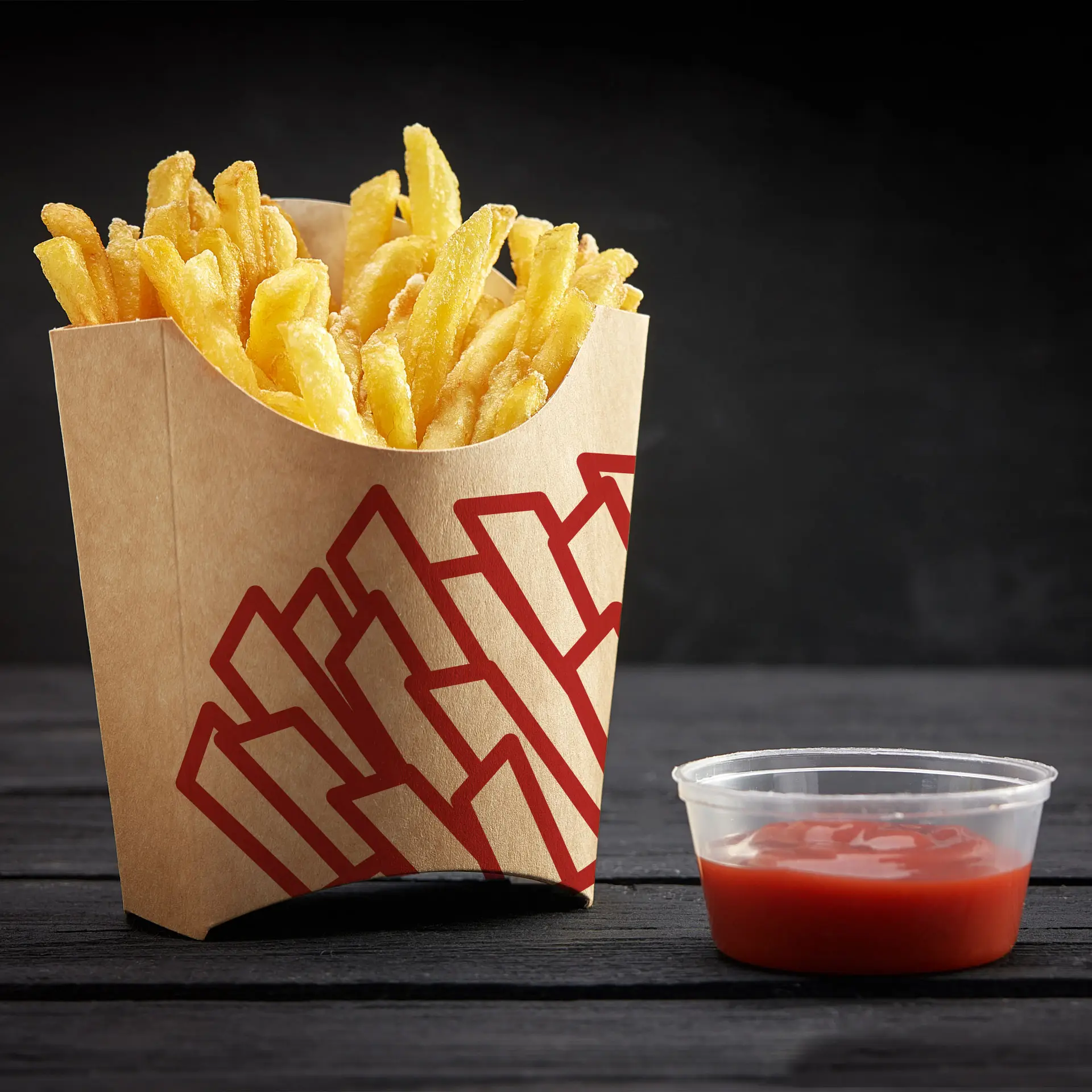 Frites de pommes de terre fraîchement frites dans un plateau en carton imprimé sur mesure ; accompagnées d'un petit contenant de ketchup.