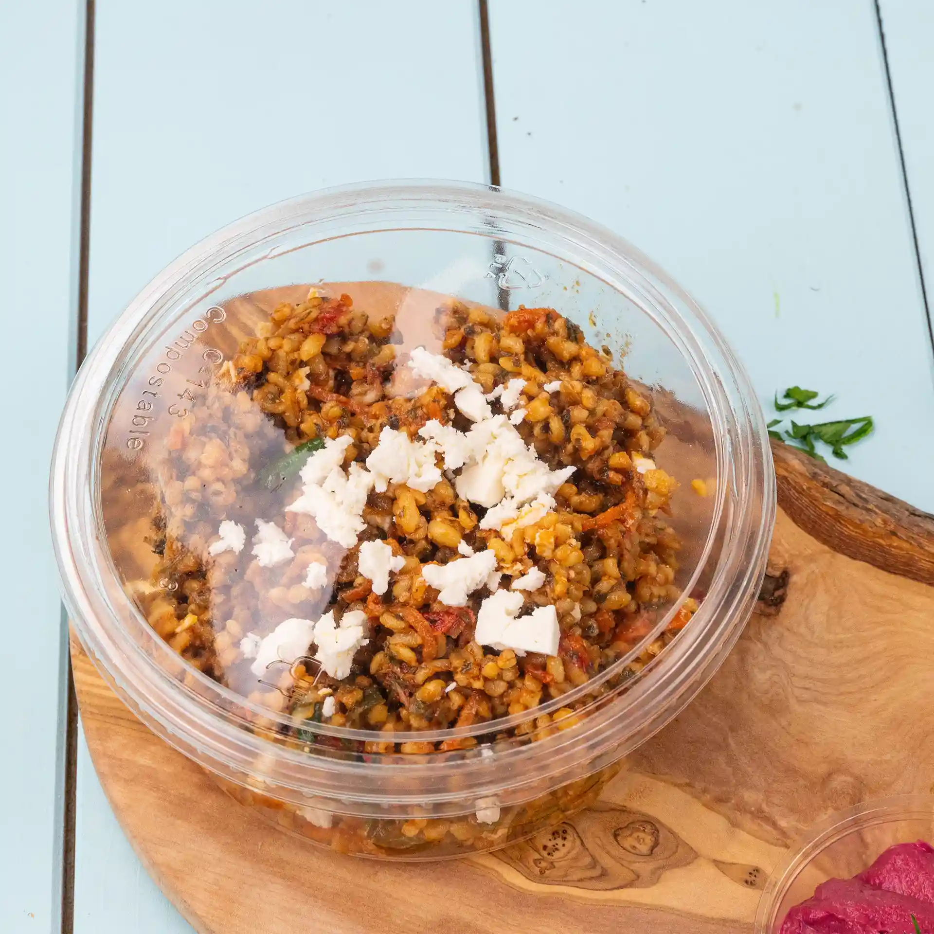 Couvercle rond transparent pour gobelet, offrant une vue claire du contenu, avec des grains et du fromage émietté sur le dessus.