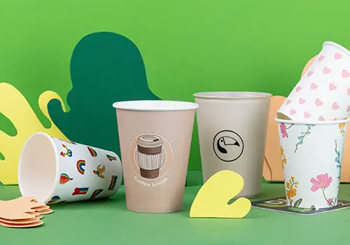 Diverses gobelets présentés sur une surface bleu clair, avec différents designs et étiquettes, incluant "Alma & Auer" et "Indie Roasters."