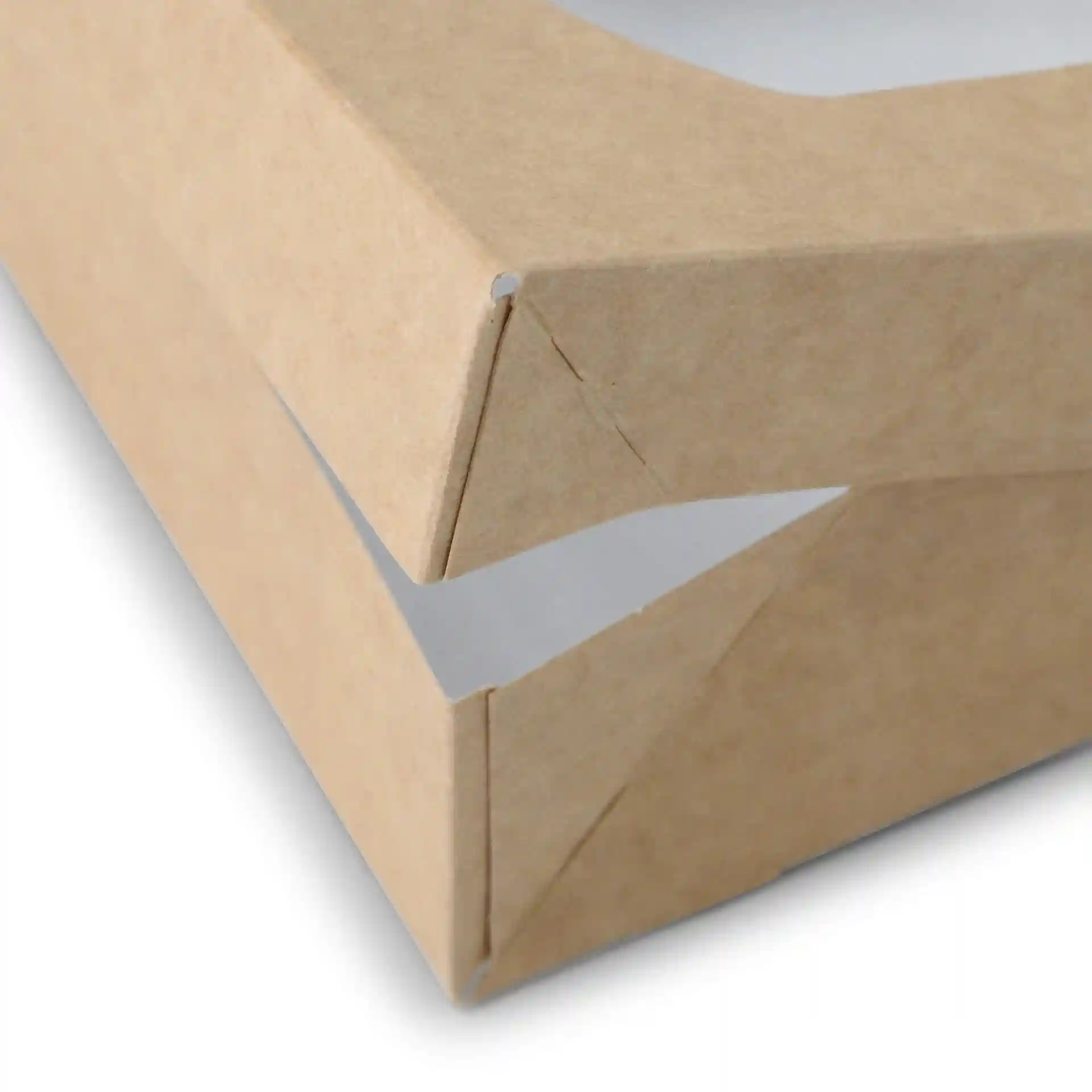 Gros plan d'une boîte en carton marron avec une conception pliable, montrant le coin et l'intérieur blanc.