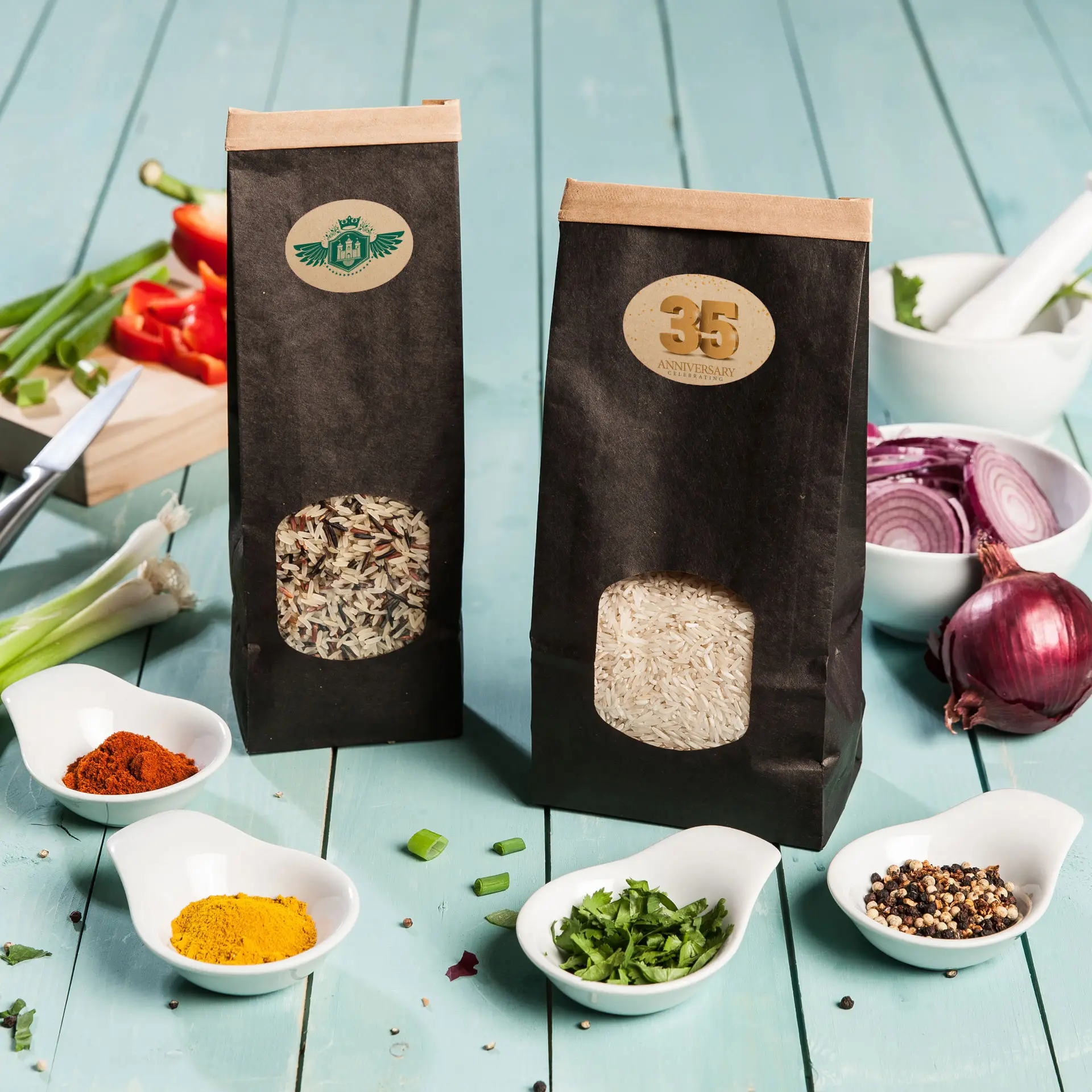 Deux sacs en papier de riz, l'un contenant du riz basmati brun et l'autre du riz blanc, posés sur une surface en bois bleu avec des épices éparpillées.