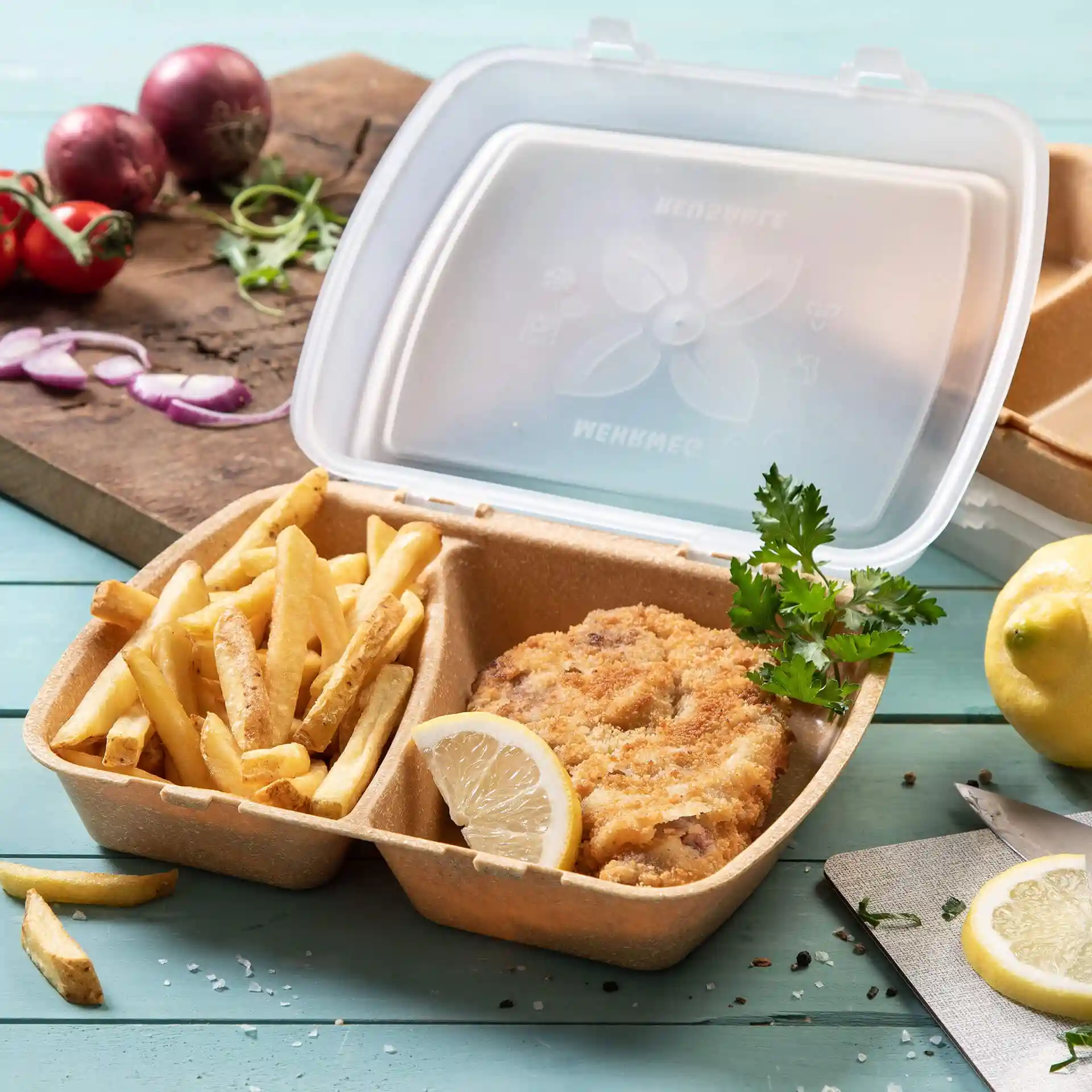 Conteneur de repas réutilisable marron avec deux compartiments, contenant du poulet frit, des frites, une tranche de citron et du persil.