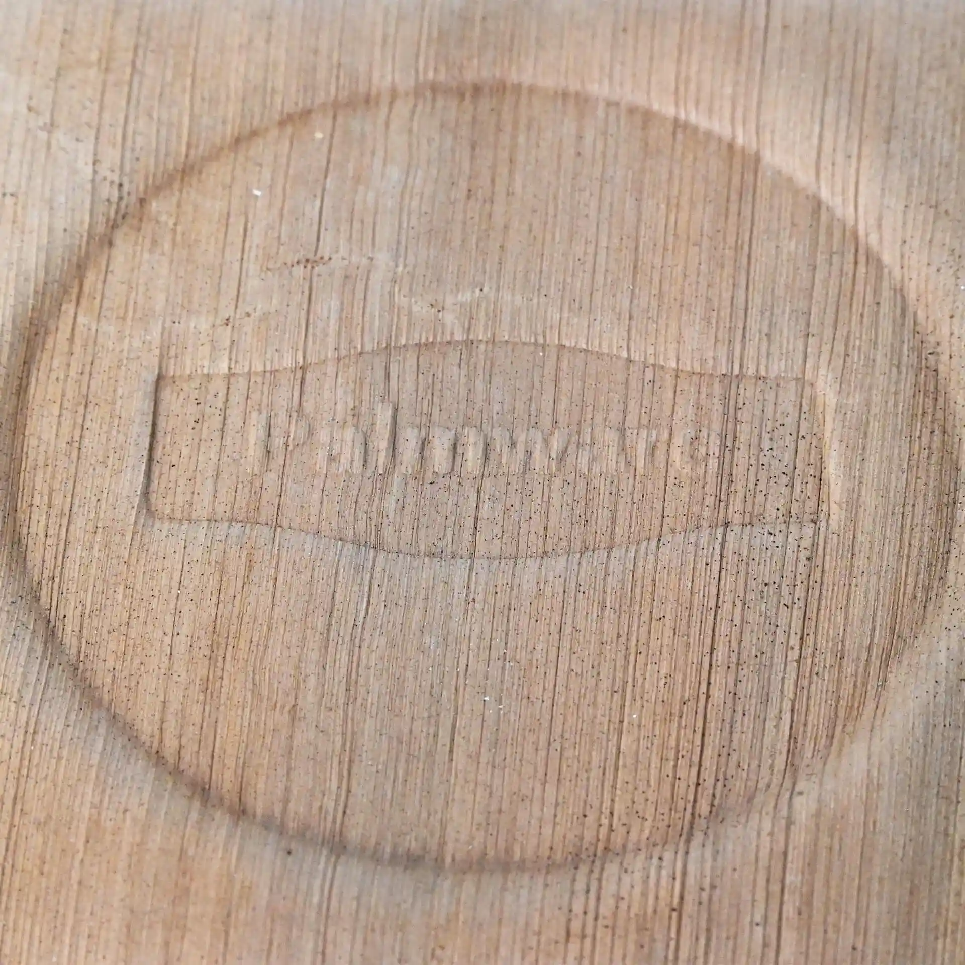Gros plan d'une surface en bois clair avec un design circulaire en relief comportant le texte "Palmware®".