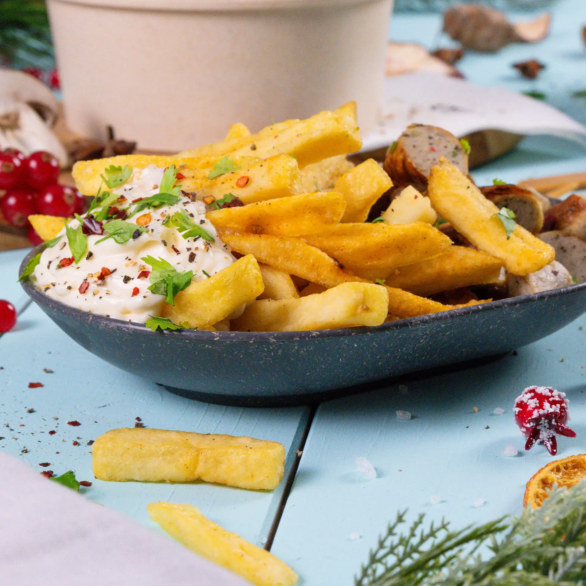 Un bol à collation ovale réutilisable rempli de frites garnies de piments rouges et de coriandre ; à proximité, des poivrons verts et rouges, une fourchette et des collations.
