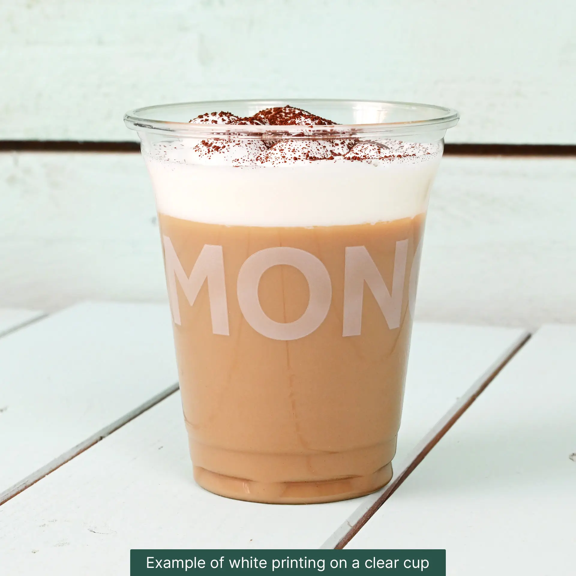 Gobelet en PLA de 10 oz rempli de café glacé, avec de la crème fouettée et de la poudre de cacao, sur fond clair.