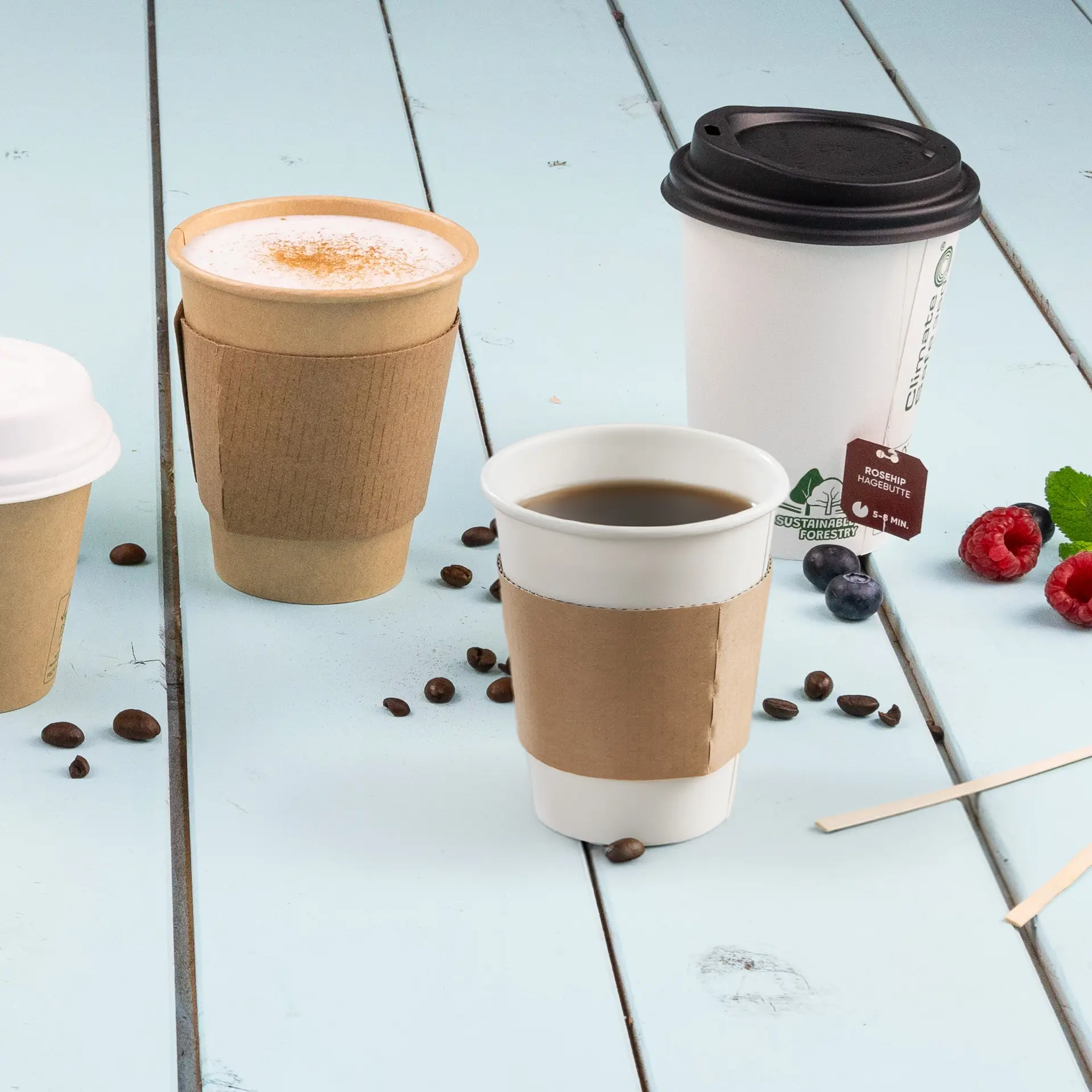 Manchon en carton brun pour gobelets en papier de 150/200/250 ml, placé sur une surface en bois bleu avec des gobelets à café.