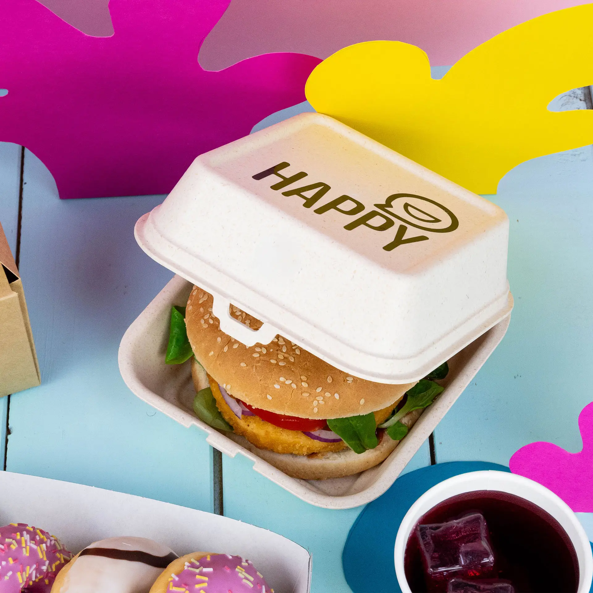 Boîte à burger crème réutilisable avec design personnalisé; adaptée aux aliments chauds et froids, présentée avec des accents latéraux et une fourchette.