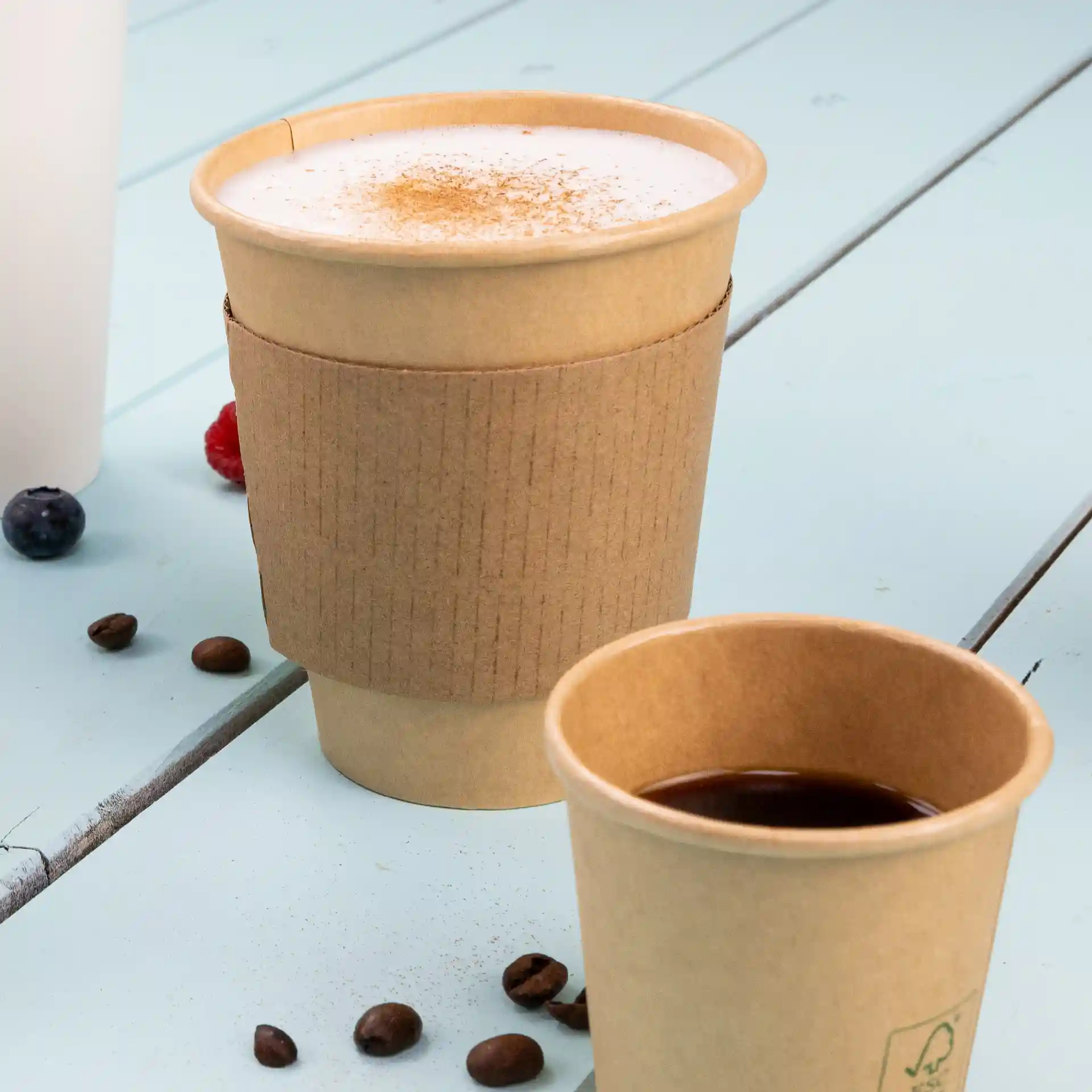 Gobelet en papier brun à paroi simple avec revêtement PLA, capacité de 300 ml, placé à côté d'un plus petit gobelet sur une surface bleue.