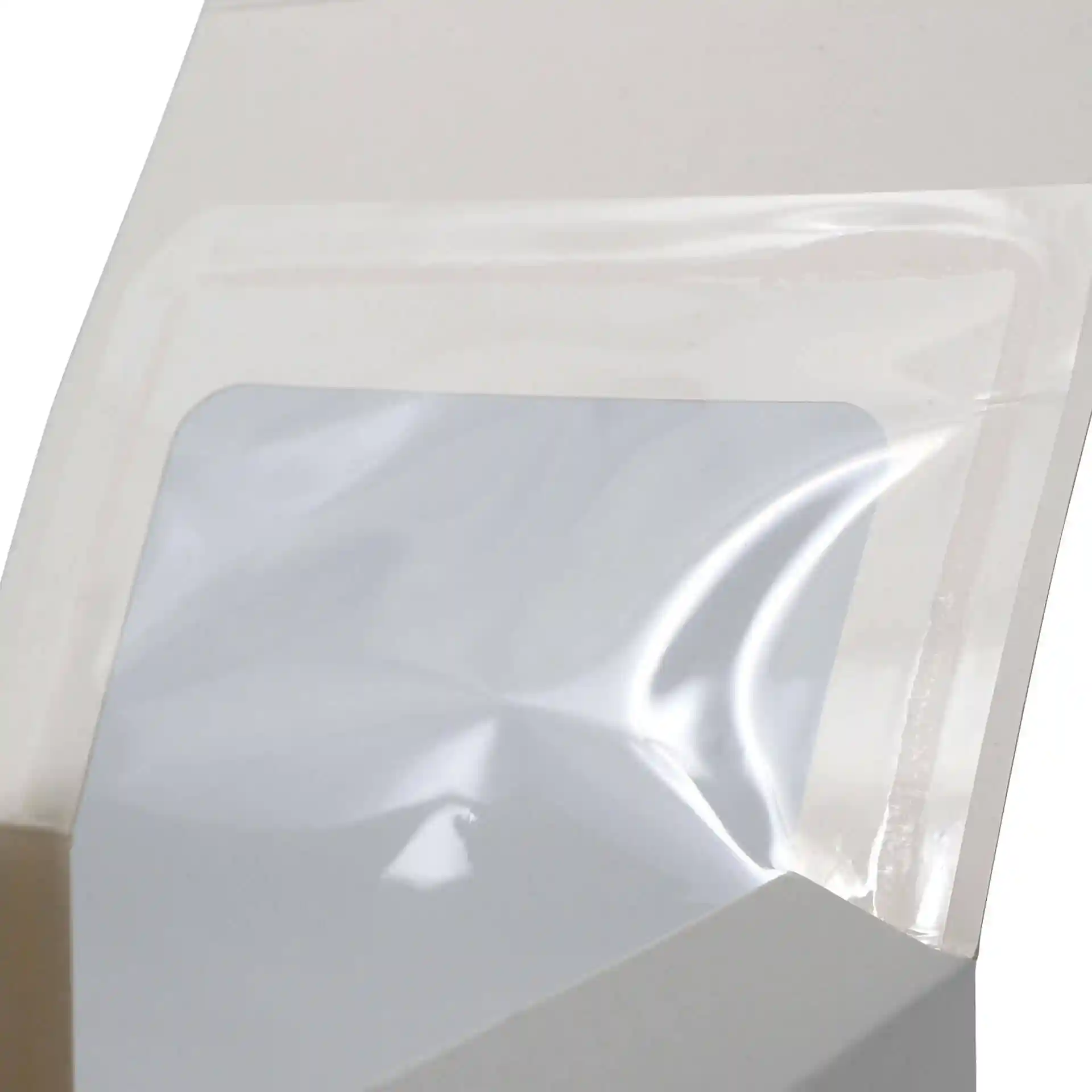Gros plan d'une boîte à pâtisserie blanche avec une fenêtre en cellulose transparente, montrant l'ouverture et la surface intérieure de la boîte.