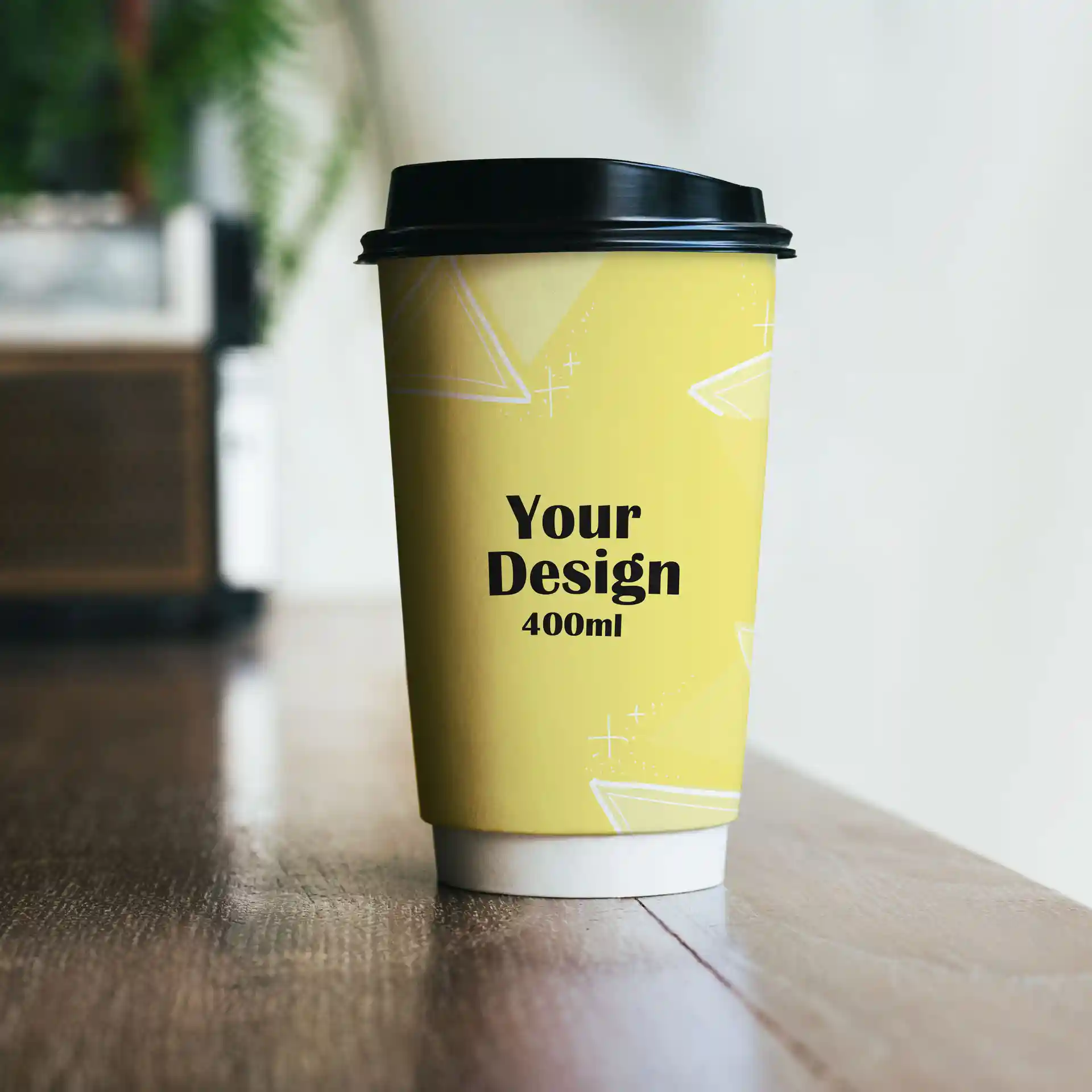 Gobelet en papier jaune avec un couvercle noir, présentant un design et un texte indiquant un volume de 400 ml.